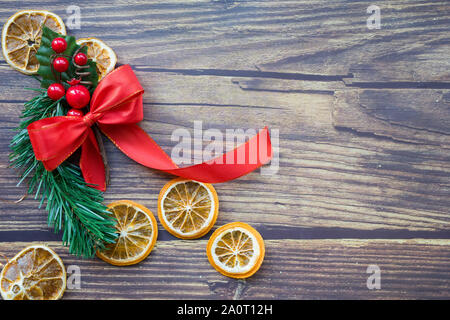 Sfondo di Natale da essiccato arance, pino ramoscello e fiocco rosso su una tavola di legno Foto Stock