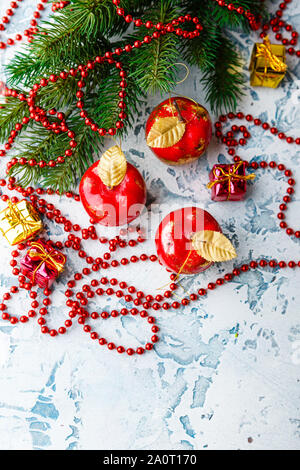 Le decorazioni di Natale in forma di mele, ramo di abete rosso e garland-perle su uno sfondo luminoso Foto Stock