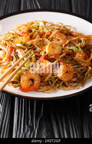 Servire di Chow Mein tagliatelle con gamberi e verdure close-up su una piastra sul piano verticale. Foto Stock