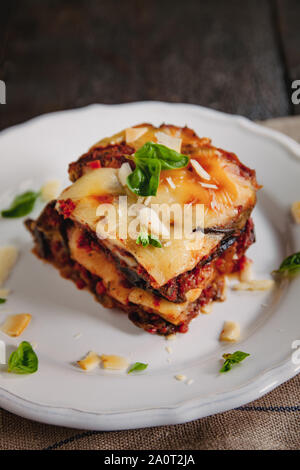 Tipologia alla Parmigiana di melanzane: Melanzane al forno - Italia, la cucina siciliana.melanzane al forno con formaggio, pomodori e spezie su una piastra bianca. Un piatto Foto Stock