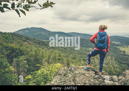 Escursionismo ragazza con zaino, guardando a vista. Viaggi e uno stile di vita sano all'aperto nella stagione autunnale. Guardando le montagne paesaggio. Foto Stock