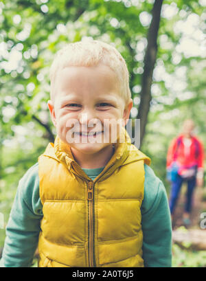 Il Toddler boy escursionismo con la madre, avventura in famiglia. Bambino a piedi nella rocciosa foresta verde, sorridente. Foto Stock