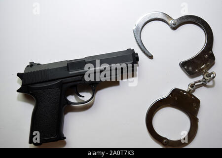 Pistola nero e manette isolati su sfondo bianco Foto Stock