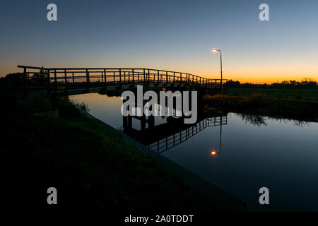 Ponte di bicicletta con la lanterna su un canale nei Paesi Bassi dopo il tramonto Foto Stock