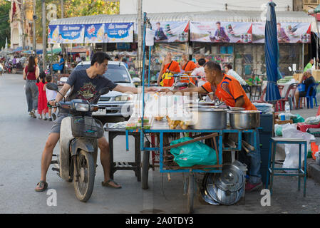 SUKHOTHAI, Tailandia - 25 dicembre 2018: il giovane uomo tailandese sullo scooter paga il cibo presso il venditore ambulante Foto Stock