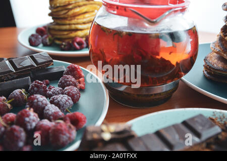 Ancora vita su piastre blu pancake con piselli, cioccolato grattugiato, barrette di cioccolato, di infuso di tè. Foto Stock
