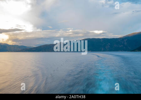 Queen Mary 2's wake attraverso ancora un fiordo Norwgian al tramonto Foto Stock
