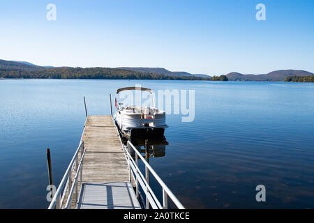 Un pontone barca legato fino al villaggio dock a Osborne punto sul Lago Pleasant in speculatore, NY USA Foto Stock