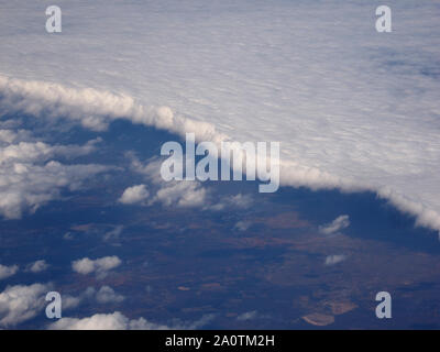 Vista aerea del bordo della fitta coltre di piatta nuvola bianca al di sopra dello Zambia, Africa dà impressione di ghiaccio-ripiano su blue, oscurata, distesa di terra Foto Stock