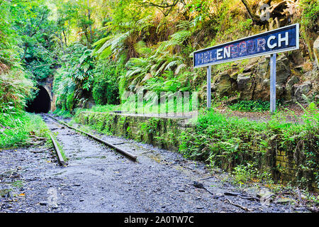 Vecchia ferrovia abbandonata via rail road tunnel in regionale città australiana Helensburgh contemplati in una lussureggiante vegetazione e vecchi binari. Foto Stock