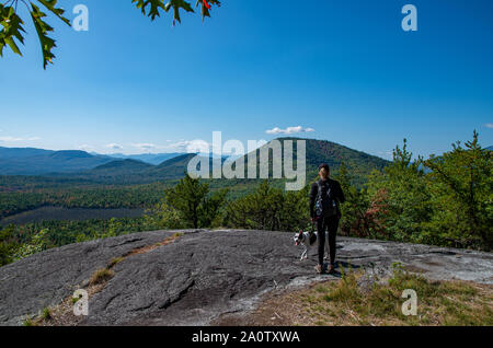 Donna e cane godendo della vista di Adirondack mountain range dalla vetta della montagna di Clark Foto Stock