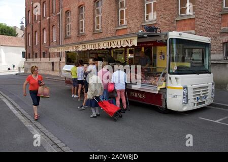 I clienti attendono di essere serviti presso un macellaio mobile in un mercato francese Foto Stock