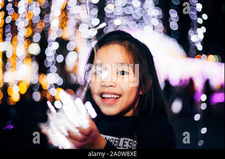 Dei bambini felici con una luce su un Capodanno.Street Scena notturna con le luci di Natale . Serata di Natale Concept Foto Stock