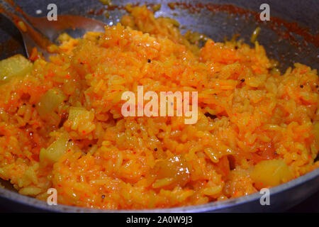 Pilaf con carne di agnello e il colore rosso granato, in un grande cast-ferro padella kazan. Immagine di sfondo. Messa a fuoco selettiva Foto Stock