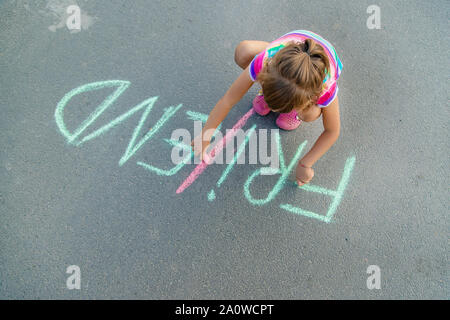 I bambini di iscrizione sull'asfalto con chalk, amici. Messa a fuoco selettiva. Foto Stock