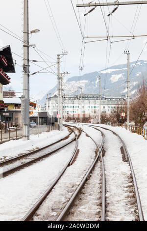 La vista lungo una coperta di neve il binario ferroviario nella città di Zell am See, Austria. Sullo sfondo si vede il Grand Hotel. Foto Stock