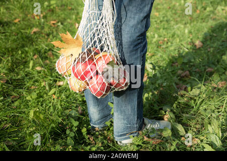 La donna trattiene shopping cotone stringa sacchetto con le mele rosse. Autunno Zero Rifiuti Nozione Foto Stock