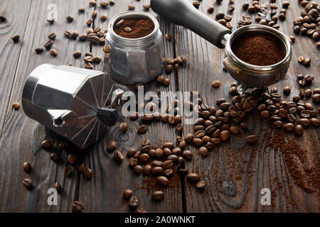 Geyser caffè vicino portafilter su una superficie di legno con i chicchi di caffè Foto Stock