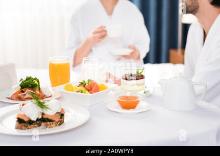 Messa a fuoco selettiva della gustosa prima colazione sul tavolo vicino all uomo e donna Foto Stock