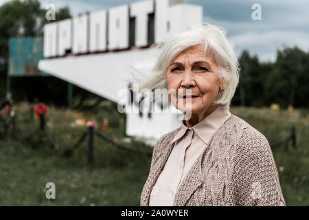 Pripjat, Ucraina - Agosto 15, 2019: senior donna in piedi vicino al monumento con pripjat lettere Foto Stock