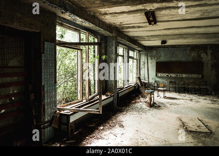 Abbandonato aula con sedie sporche nella scuola Foto Stock