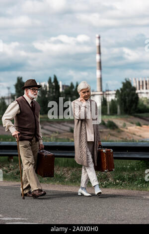 Pripjat, Ucraina - Agosto 15, 2019: senior l uomo e la donna a piedi con i bagagli vicino alla centrale nucleare di Cernobyl Foto Stock