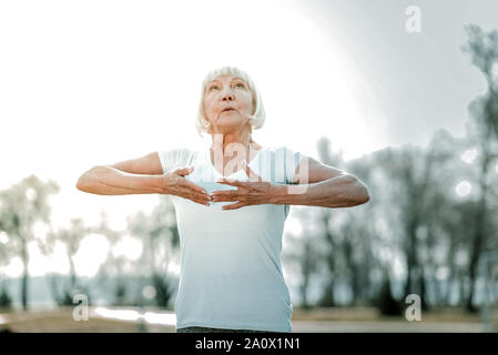 Calming anziani missis facendo esercizi di respirazione all'aria aperta Foto Stock