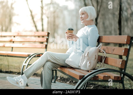 Blu-risciacquata concernedly donna seduta con bicchiere di carta sul banco di lavoro Foto Stock