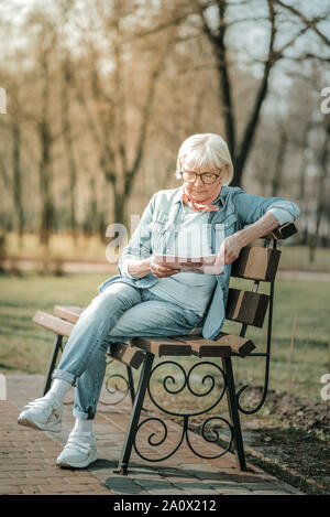 Ammaliante senior mam impegnandosi nella lettura di una rivista Foto Stock