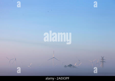 Le turbine eoliche di prima mattina nebbia sulla campagna di ostfriesland in Bassa Sassonia Foto Stock