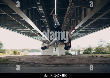 Parkour giovane uomo facendo acrobazie e trick flip jumping alta Foto Stock