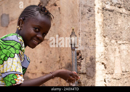 Felice bambino africano ottiene finalmente accesso a di acqua dolce pulita Foto Stock