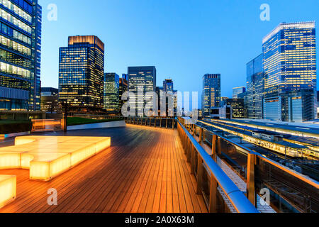 Tokyo, Marunouchi. KITTE edificio, il giardino sul tetto illuminato di notte con la stazione di Tokyo e alta nei dintorni di edifici. Ora blu. Foto Stock