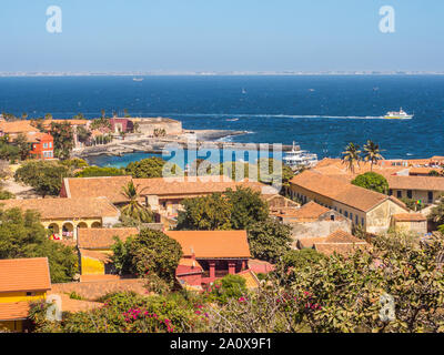 Gorea, Senegal - Febbraio 2, 2019: Vista di case con il tetto rosso sull'isola di Goree con Dakar in background. Gorée. Dakar, Senegal. L'Africa. Foto Stock