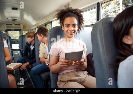 Compagni di classe andando a scuola in autobus la ragazza seduta close-up utilizzando app su tavoletta digitale sorridente gioiosa Foto Stock