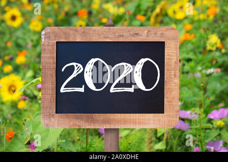 2020 scritto su un rustico di legno, estate girasoli e fiori selvatici in background Foto Stock