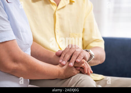 Close up Asian coppia senior incoraggiare insieme tenendo la mano di ogni altra al divano nel soggiorno di casa.felice lo stile di vita di pensionamento.invecchiamento a home Foto Stock