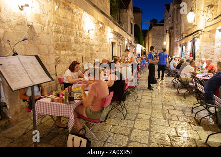Viaggio Dubrovnik - persone mangiare all'aperto presso un ristorante nelle strette stradine del borgo medievale di Dubrovnik Città Vecchia, Dubrovnik Croazia Europa Foto Stock