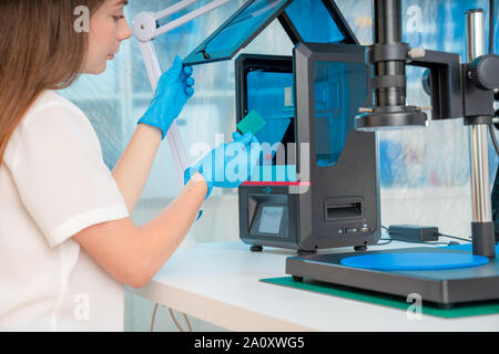 Lavoratore di sesso femminile nel controllo di resina LCD / DLP / SLA stampante 3D nel laboratorio di tecnologia Foto Stock