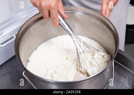 Mix di casaro latte cagliato con una frusta da cucina Foto Stock