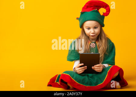 Elf si siede sul pavimento controllare l'elenco e assicurandosi che essi hanno tutti i regali Foto Stock