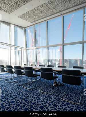 Luce, sunny boardroom con tubolare piegato sedie in acciaio e tappeti blu con disegno geometrico, all'Aga Khan Centro, Kings Cross, London, Regno Unito. Foto Stock