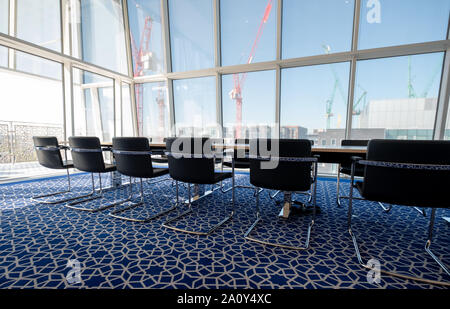Luce, sunny boardroom con tubolare piegato sedie in acciaio e tappeti blu con disegno geometrico, all'Aga Khan Centro, Kings Cross, London, Regno Unito. Foto Stock