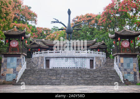 Fenghuang, Cina. Settembre 13, 2015. Una statua di Phoenix e fioritura golden pioggia alberi all'interno di un parco di Fenghuang antica città nella provincia del Hunan chi Foto Stock