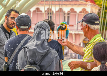 7 19 2019 Tbilisi Georgia -ponte pedonale della pace - la donna in hijab con grazioso zaino con le orecchie e gli occhiali da sole - marito conversed intensamente con Foto Stock