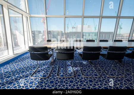 Luce, sunny boardroom con tubolare piegato sedie in acciaio e tappeti blu con disegno geometrico, all'Aga Khan Centro, Kings Cross, London, Regno Unito. Foto Stock