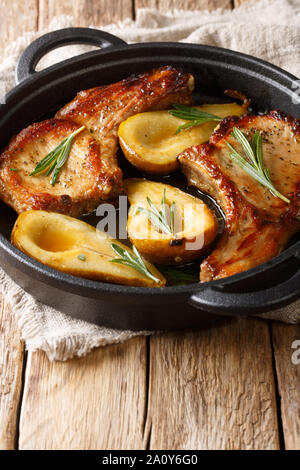 Autunno cibo costolette di maiale con nervature al forno con pere e rosmarino in salsa di miele in una padella vicino sul piano verticale. Foto Stock