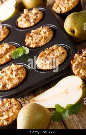 Muffin pera con cannella e noci in una teglia da forno da vicino sul piano verticale. Foto Stock