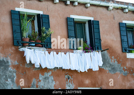 Biancheria stesa ad asciugare su una linea di lavaggio dalle finestre di una casa tradizionale su l'isola di Murano, Italia Foto Stock