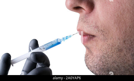 Iniezione di botox in un giovane uomo caucasico labbra. Siringa con liquido blu e un ago in una mano con il nero di guanto protettivo. Isolato su bianco backgr Foto Stock